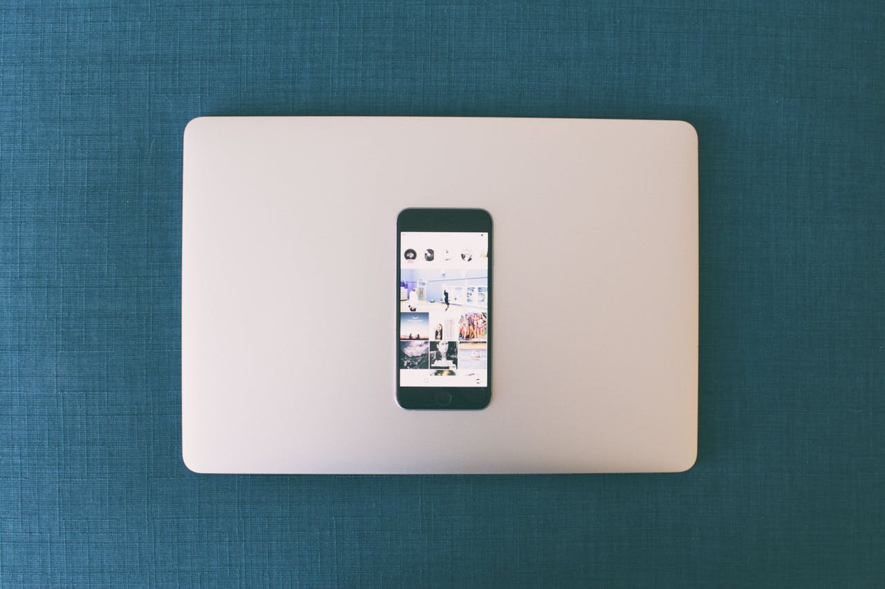 Home Flat lay of a smartphone on a laptop with social media photos on screen.